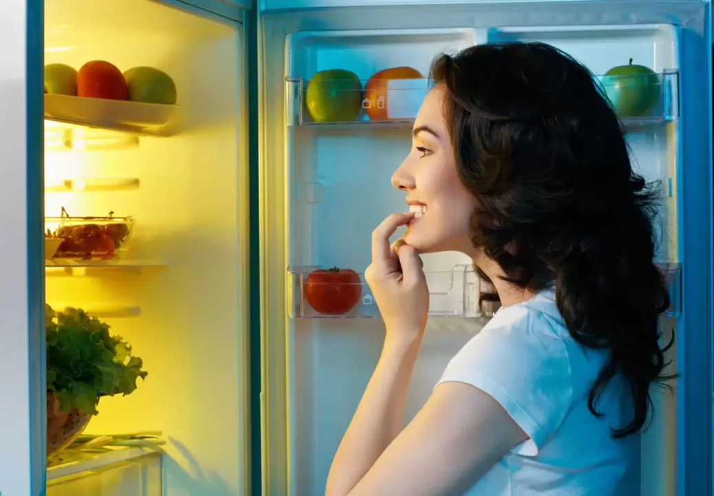 The girl looks in the fridge during rapid weight loss